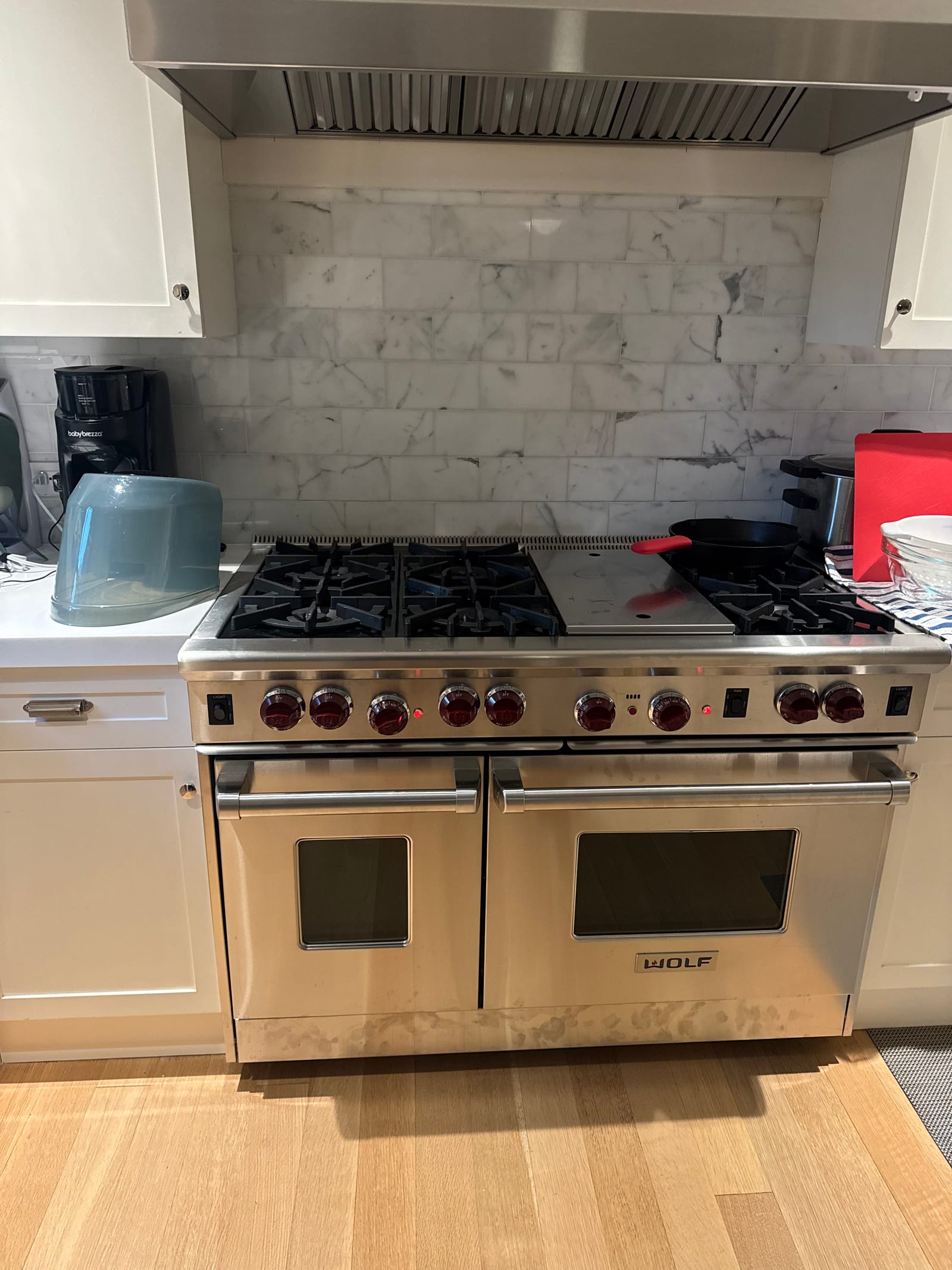 Wolf 48-inch dual-fuel range serviced in Manhattan kitchen — red knobs, double oven, marble backsplash